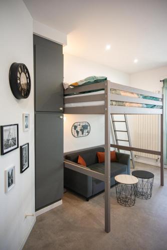 un lit superposé dans une chambre avec un canapé et une horloge dans l'établissement L'Escale, Proche ville, Parking, Terrasse, Netflix, à Montbéliard