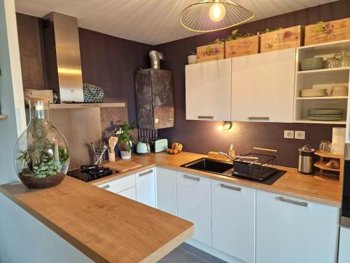 une cuisine avec des armoires blanches et un comptoir en bois dans l'établissement Le Cocon Botanique Rennais, à Saint-Jacques-de-la-Lande