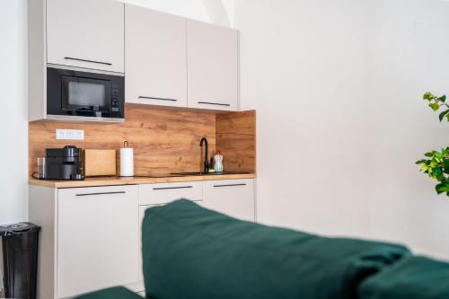 a kitchen with white cabinets and a sink and a microwave at Luxapart IV Beautiful Views with Breakfast in Košice