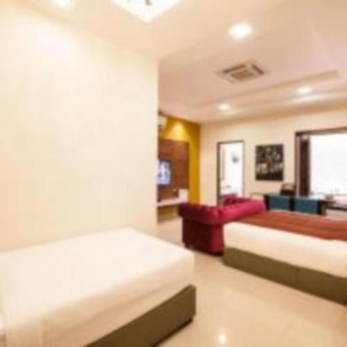 a bedroom with two beds and a red couch at Sunday Telaga Terrace Boutique Resort in Pantai Cenang