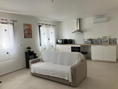 un salon avec un canapé blanc et une cuisine dans l'établissement Sérénité au Coeur de la Provence, à Cuges-les-Pins