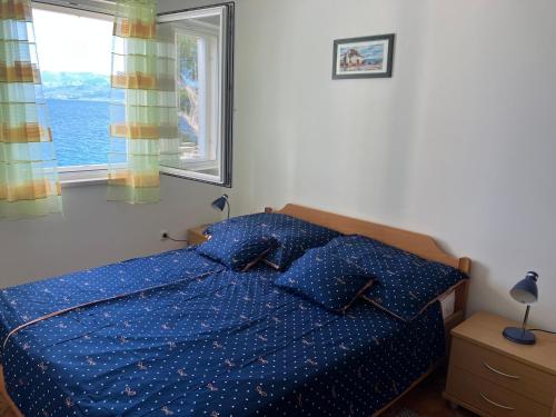 a bedroom with a blue bed with pillows and a window at Apartment Andrea in Sutivan