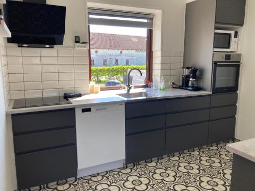 a kitchen with a sink and a window at Lille Røde hus Mandø in Ribe