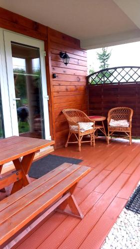 a deck with two benches and a table and chairs at Domki Obłazówka nad Białką in Nowa Biała
