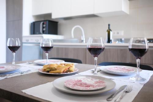 einen Tisch mit zwei Gläsern Wein und Teller mit Speisen in der Unterkunft Pietrenere39 in Pozzallo