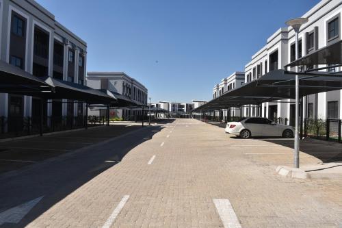 an empty street with a car parked next to buildings at Sarona City Kappa CasaHaven Apartments in Gaborone