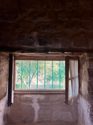 a window in a stone building with a curtain at Hartna zaman in Taiyiba