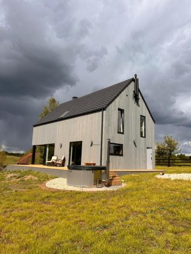 a gray barn with a black roof on a field at Powidoki Mazury in Płociczno