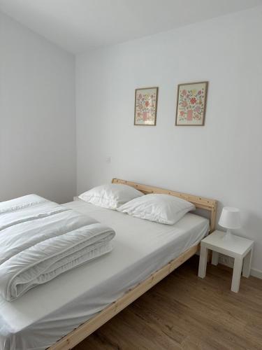 - une chambre avec un lit avec des draps blancs et une table dans l'établissement Maison neuve entre la Plage, Aréna et de la gare des sables d'olonne, à Les Sables-dʼOlonne
