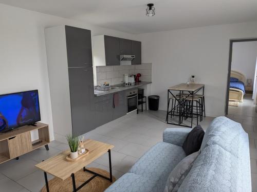 un salon avec un canapé bleu et une cuisine dans l'établissement O'Bel Air 2, à Amboise