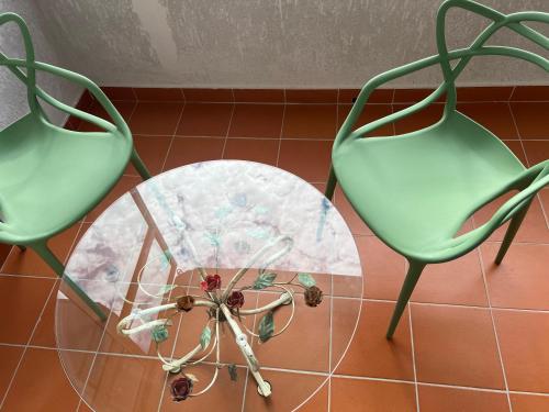 two green chairs and a glass table with a fan at B&BMarì in Pontecagnano