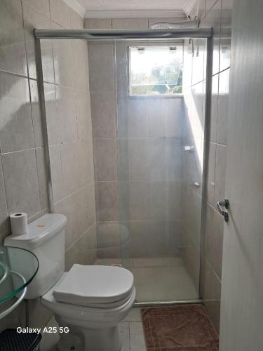 a bathroom with a shower with a toilet and a window at Pousada Vô Joel in Blumenau