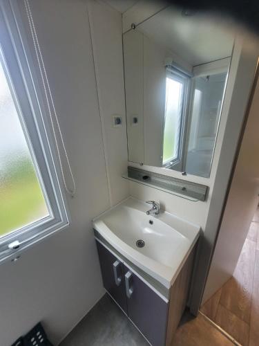 une salle de bain avec un lavabo et un miroir dans l'établissement mobil home, à Lit-et-Mixe