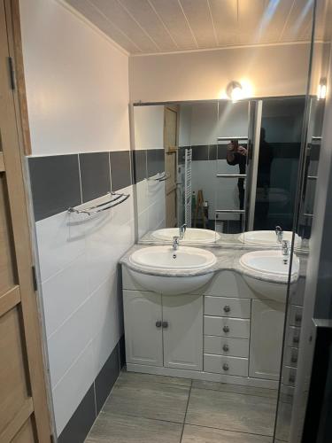 une salle de bain avec deux lavabos et un homme prenant une photo dans l'établissement Chez Claude, à La Celle-sous-Gouzon
