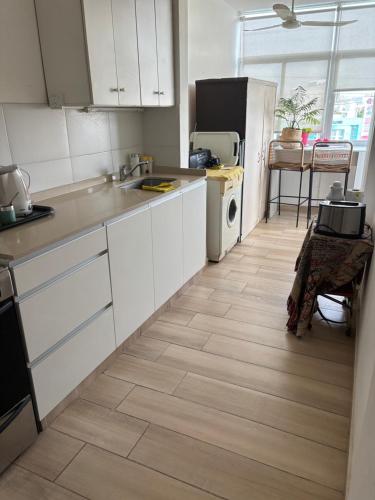 cocina con armarios blancos y suelo de madera en Departamento La Rotonda, en Santa Rosa