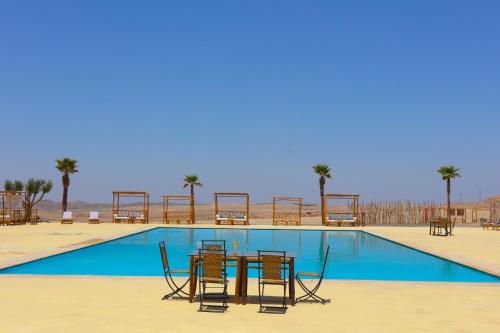 a table and chairs in front of a swimming pool at Kal Tenere Agafay Luxury Camp in El Karia
