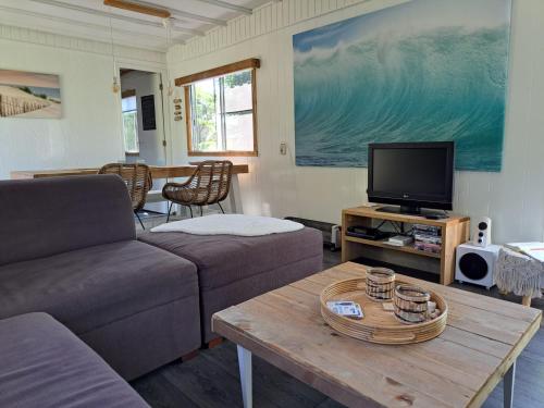 a living room with a couch and a table with a tv at Zeeuwse Landhoeve Chalet in Brouwershaven