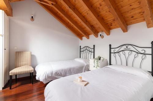 a bedroom with two beds and a chair at Duplex cerca de la playa con piscina in Miengo