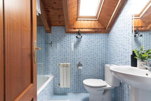 a bathroom with a toilet and a sink at Duplex cerca de la playa con piscina in Miengo