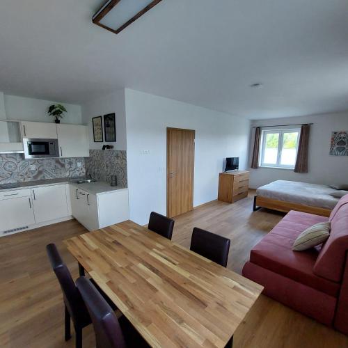 a living room with a wooden table and a kitchen at Apartmány Hluchá Bašta s vnitřním bazénem in České Budějovice