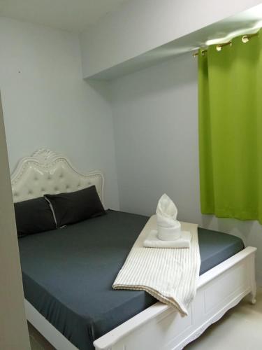 a bedroom with a bed with a green curtain at Sea Residences david in Manila