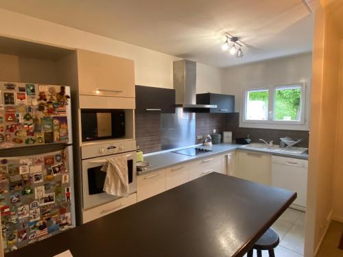 a kitchen with a table and a refrigerator at Family home in Mérignac