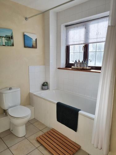 a bathroom with a tub and a toilet and a window at Bay Tree Cottage - cosy home near beach in Woolacombe