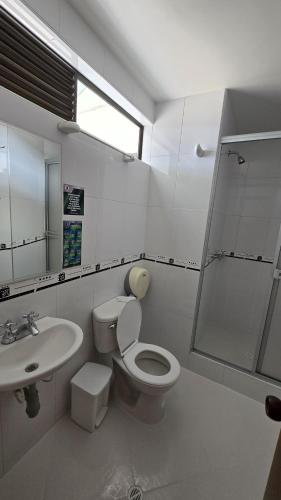 a white bathroom with a toilet and a sink at Hotel Imperial in Chiquinquirá