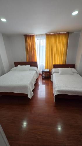 two beds in a room with wooden floors and windows at Hotel Imperial in Chiquinquirá