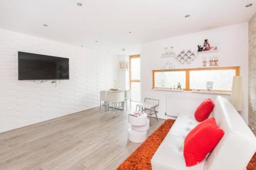 a white living room with a white couch and red pillows at Newly Furnish 2 bedroom Flat in Barking
