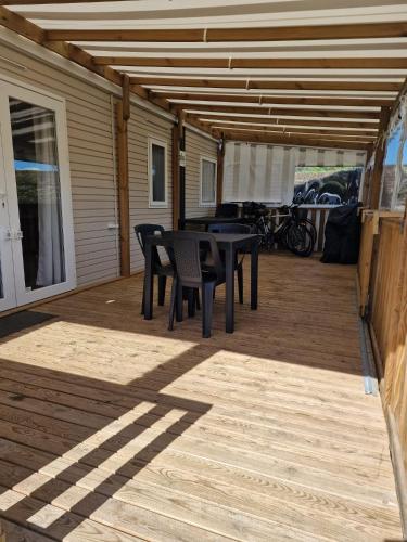 un patio avec tables et chaises sur une terrasse dans l'établissement Mobil Home tout equipé Camping Siblu 4etoiles Les Charmettes, aux Mathes