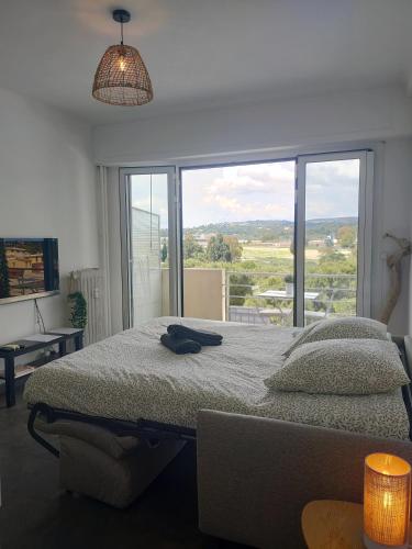 une chambre avec un lit et une grande fenêtre dans l'établissement Appartement vue mer, à Cagnes-sur-Mer