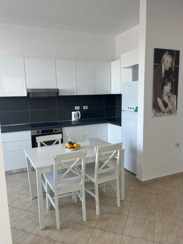 a white kitchen with a white table and chairs at Beachfront Marilyn in Durrës