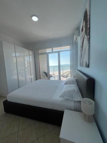 a bedroom with a large bed and a large window at Beachfront Marilyn in Durrës