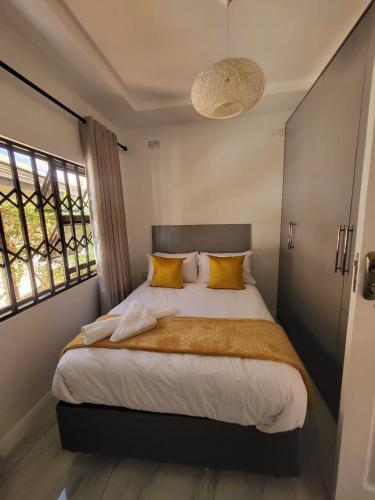a bedroom with a large bed with yellow pillows at Peanut Cottage Bulawayo in Bulawayo