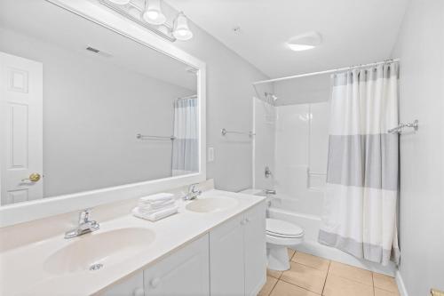 a white bathroom with a sink and a toilet at Pier Watch Unit 106-10 beds-6 bedrooms-Sleep14-Golf Cart Allowed in North Myrtle Beach