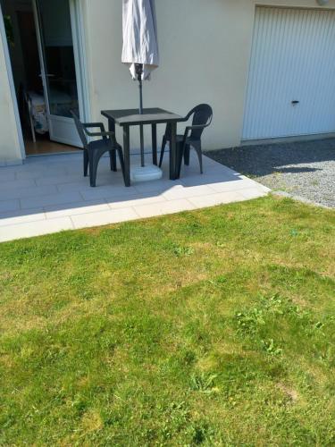 une table avec deux chaises et un parasol sur une pelouse dans l'établissement La chambre de Carole, à Aucey-la-Plaine