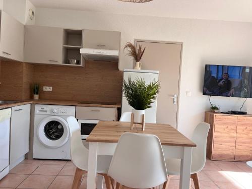 une cuisine avec une table en bois et des appareils électroménagers blancs dans l'établissement Apparemment RdC climatisé avec piscine, terrasse et parking - App 1502, à Gruissan
