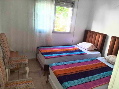 deux lits dans une chambre avec une fenêtre dans l'établissement Ennasr 1 - appartement Charmant S1 Calme et Connecté, à Ariana