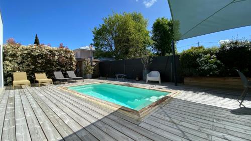 une cour arrière avec une piscine et une terrasse en bois dans l'établissement Villa des Pins, à Andernos-les-Bains
