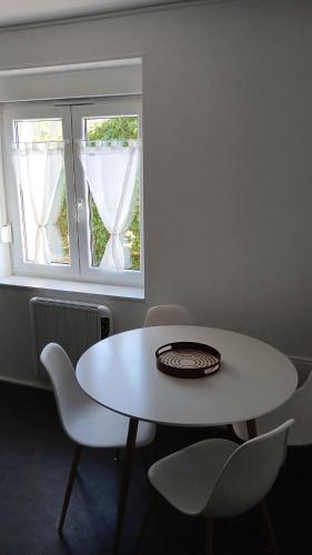 une table blanche et des chaises dans une pièce avec une fenêtre dans l'établissement Chez Anna, à Sanry-lès-Vigy