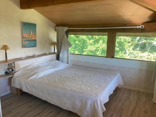 a bedroom with a bed and a large window at Gavial - Grande maison avec piscine in Léon