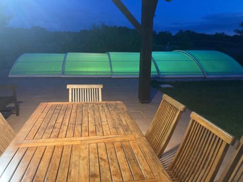 une table et des chaises en bois avec un banc en arrière-plan dans l'établissement Gavial - Grande maison avec piscine, à Léon