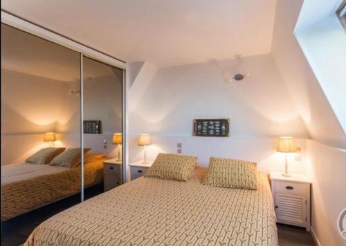 une chambre avec deux lits et un miroir dans l'établissement La vague salée, à Hermanville-sur-Mer