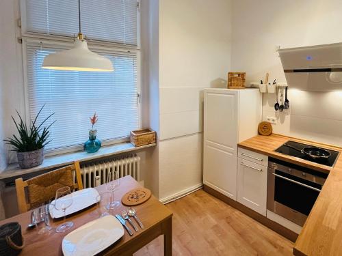 a kitchen with a table and a white refrigerator at Modernes City-Apartment mit Highspeed-WLAN & Top-Lage - Easy Stay Wuppertal in Wuppertal
