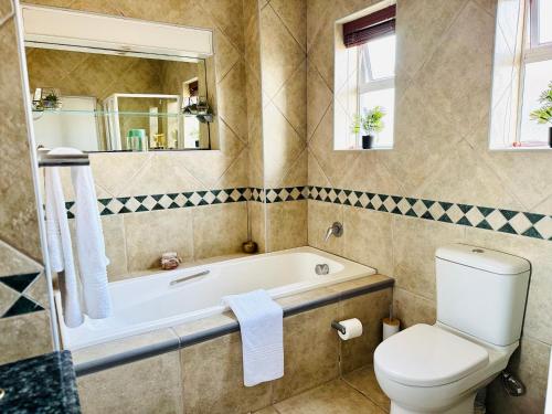 a bathroom with a tub and a toilet and a sink at Cape Golf Villa in Cape Town