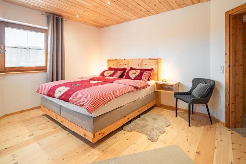 ein Schlafzimmer mit einem Bett, einem Stuhl und einem Fenster in der Unterkunft Luxus Chalet im Allgäu - Zirbenholz Schlafzimmer - Terrasse mit Bergblick - Infrarotkabine in Blaichach