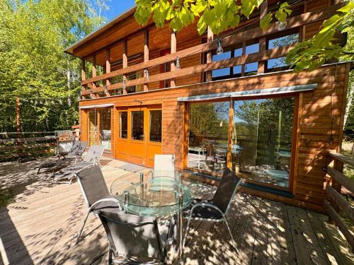 a house with a glass table and chairs on a deck at Domek nad skálou in Kunratice