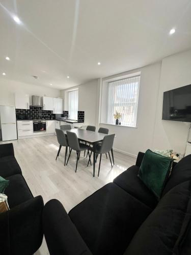 a living room with a black couch and a table at Welsh Getaway Apartment 2 - Town Centre in Dowlais