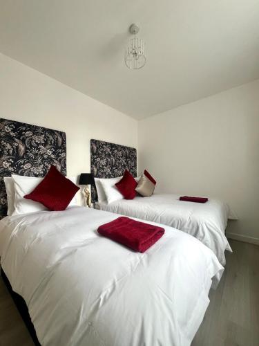 two white beds with red pillows in a room at Welsh Getaway Apartment 2 - Town Centre in Dowlais